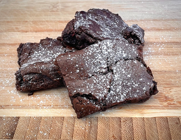 Vegan tahini brownies in stack with icing sugar dusting